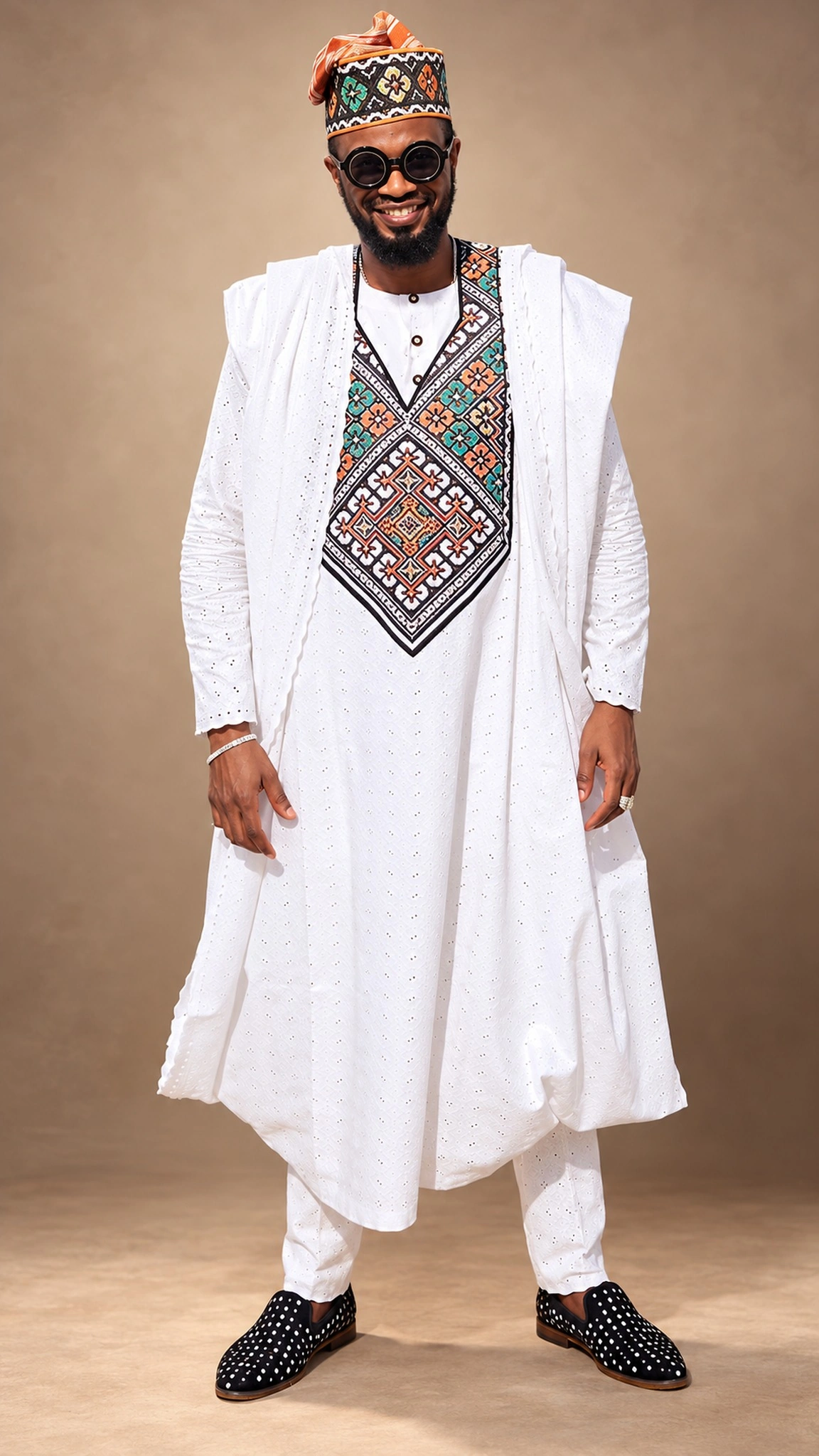 White Agbada with intricate multicoloured embroidery, styled with a matching traditional cap